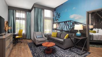 Ein Hotelzimmer mit einem Bett, einem Sofa, einem Sessel, einem Schreibtisch und einem Fernseher.