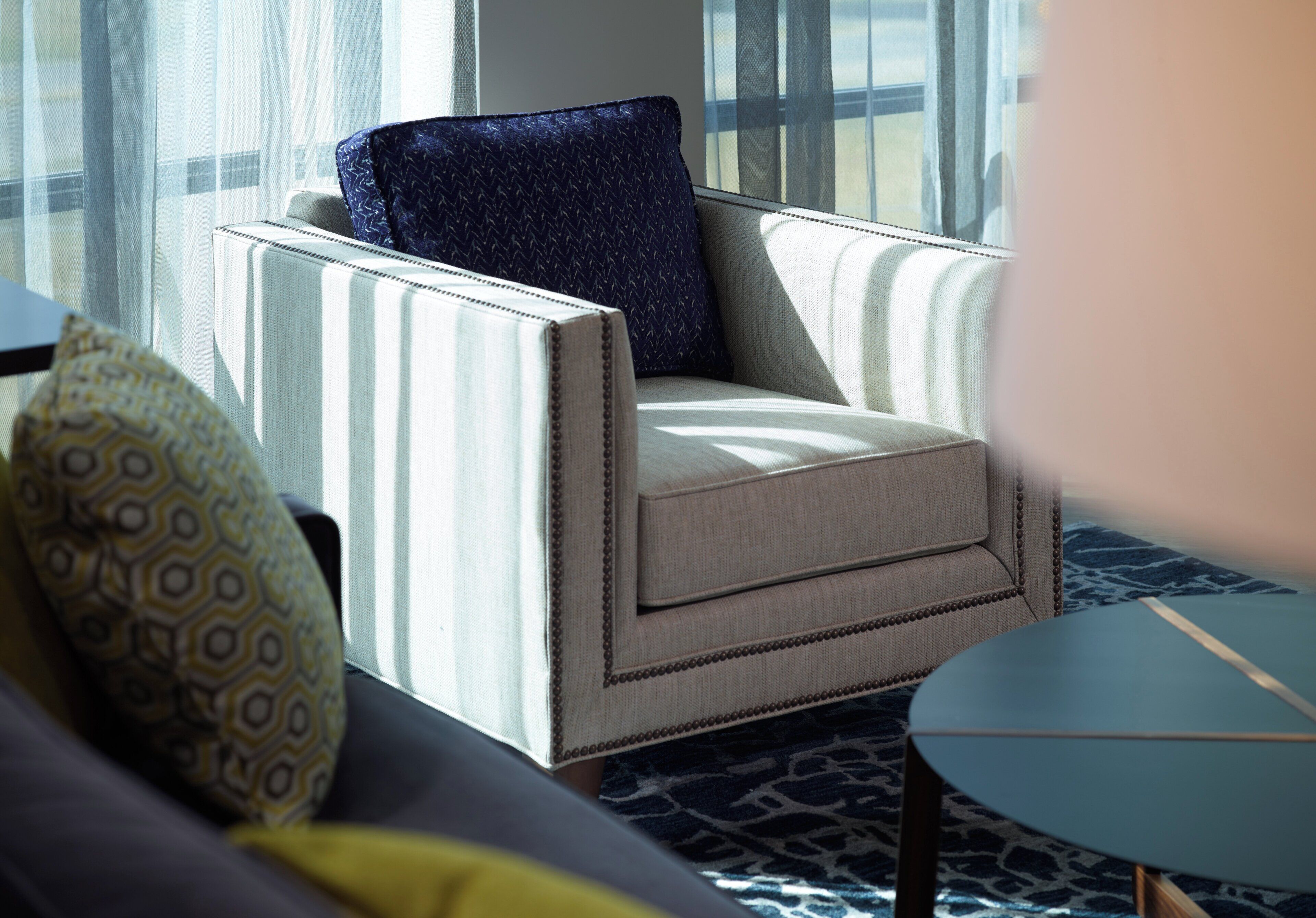 A room with a striped armchair, a patterned pillow, and a small round table.