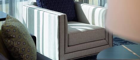 A room with a striped armchair, a patterned pillow, and a small round table.