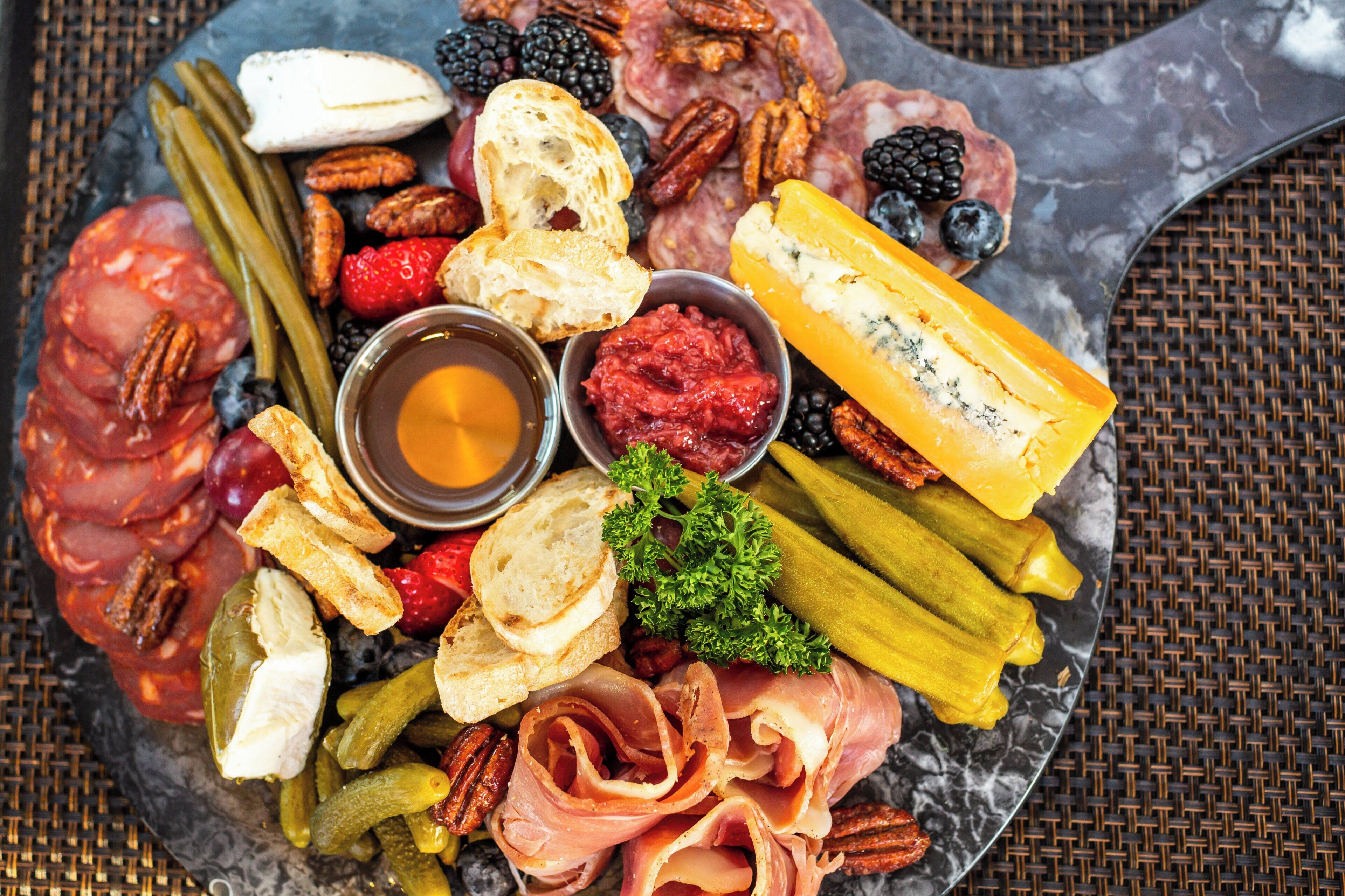 A charcuterie board with various meats, cheeses, fruits, and nuts.