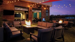 An outdoor seating area with sofas and chairs, a fire pit, and string lights. - Hotel Indigo Tuscaloosa Downtown by IHG (Tuscaloosa)