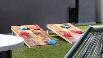 Deux tables en bois, sur lesquelles sont posés des coussins, se trouvent sur une pelouse.