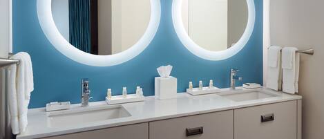 Un baño moderno con dos espejos redondos, un lavabo blanco y un mueble de tocador con cajones.