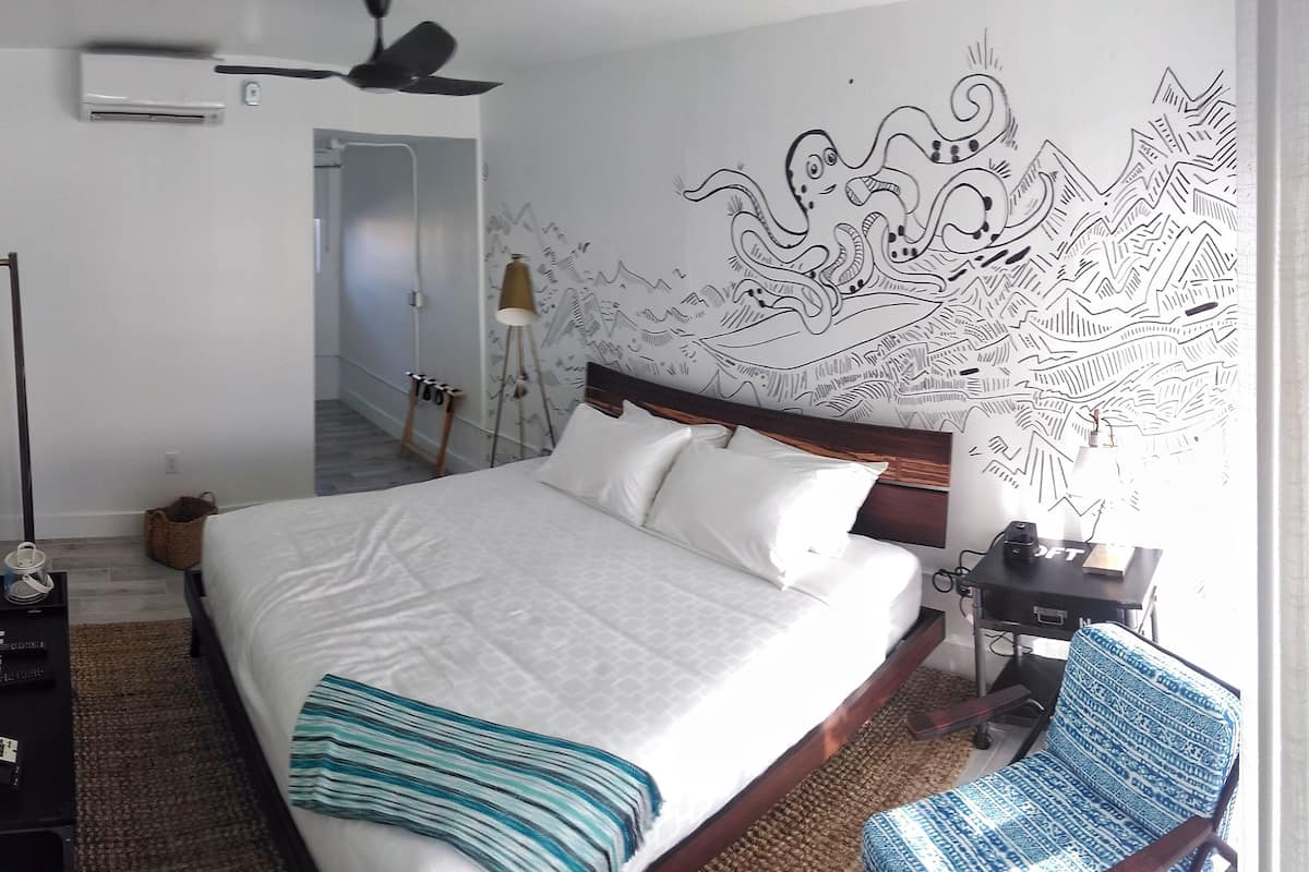A neatly arranged hotel room with a large bed, a flat-screen TV, a desk with a lamp, and a chair.
