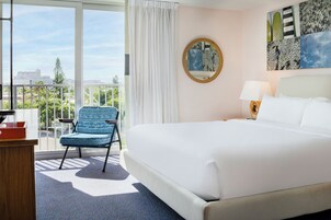 Habitación de hotel con una cama grande, una silla, un escritorio y vistas a la ciudad.