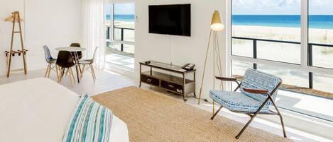 A spacious bedroom with a large bed, a television, and a view of the beach.