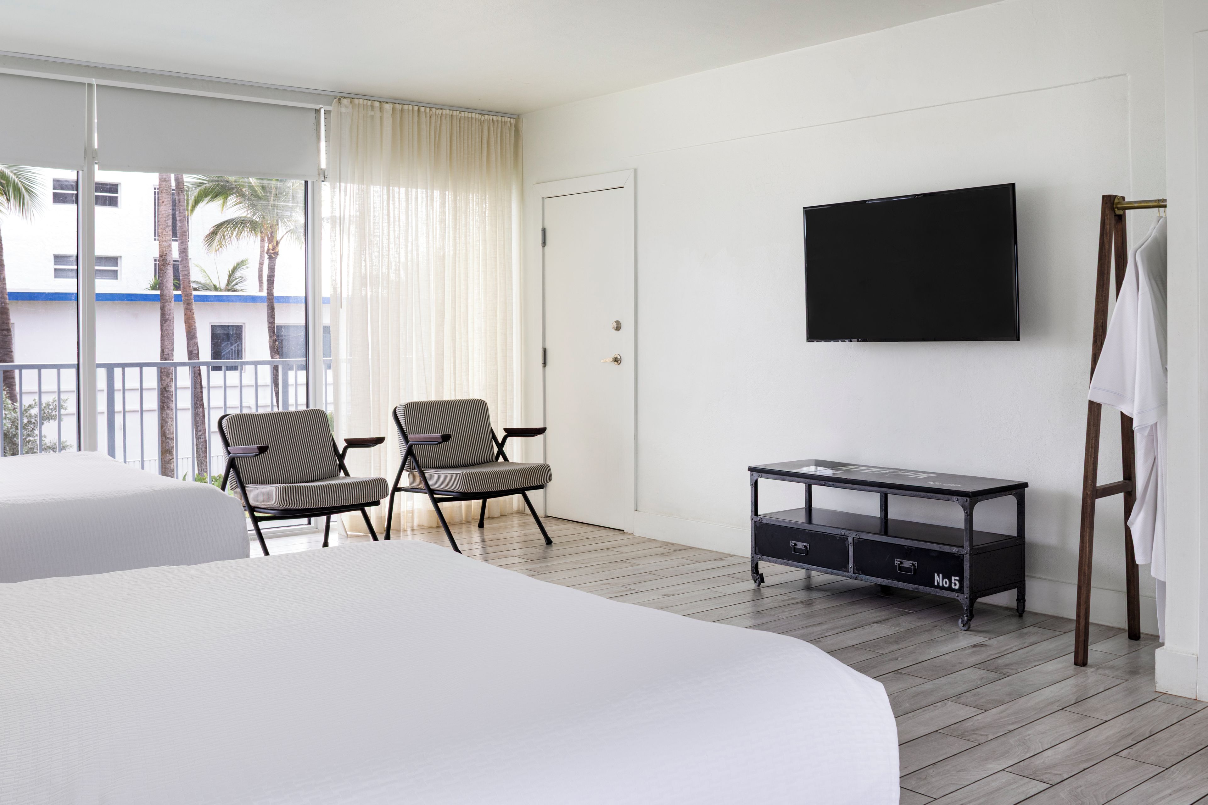 Una habitación de hotel con dos camas, televisión, escritorio y una silla.