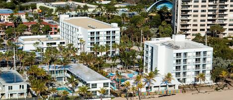 Un hotel frente al mar con varios pisos, piscina y zona de playa.