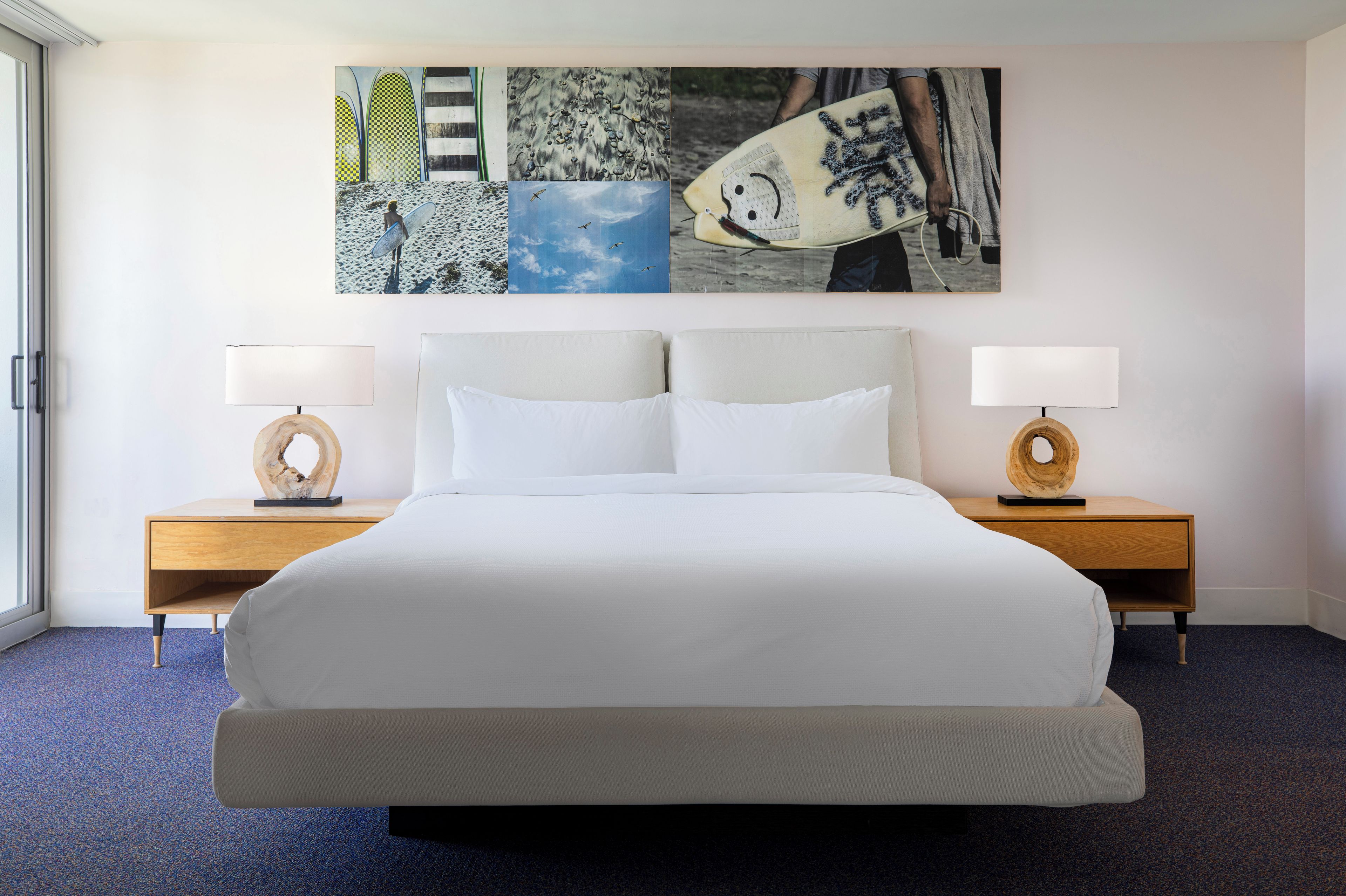 A hotel room with a large bed, two bedside tables, and a wall with a collage of artwork.