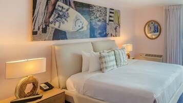 A hotel room with a large bed, two bedside tables with lamps, a decorative mirror, and a wall art piece.