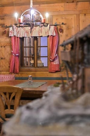 A wooden interior with a dining table, chairs, a chandelier, and curtains. - Hotel Kärntnerhof (Heiligenblut)