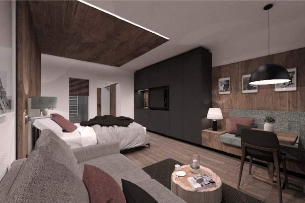 A modern hotel room with a large bed, a sofa, a dining area, and a wooden ceiling.