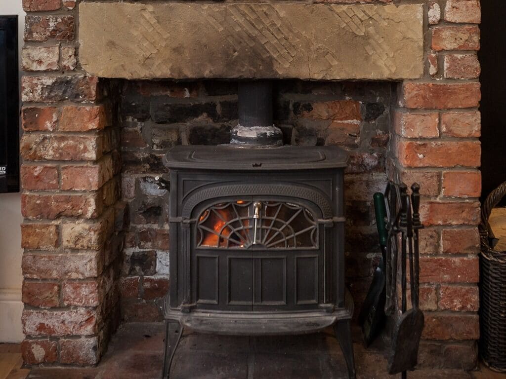 A wood-burning stove with a brick wall and chimney.