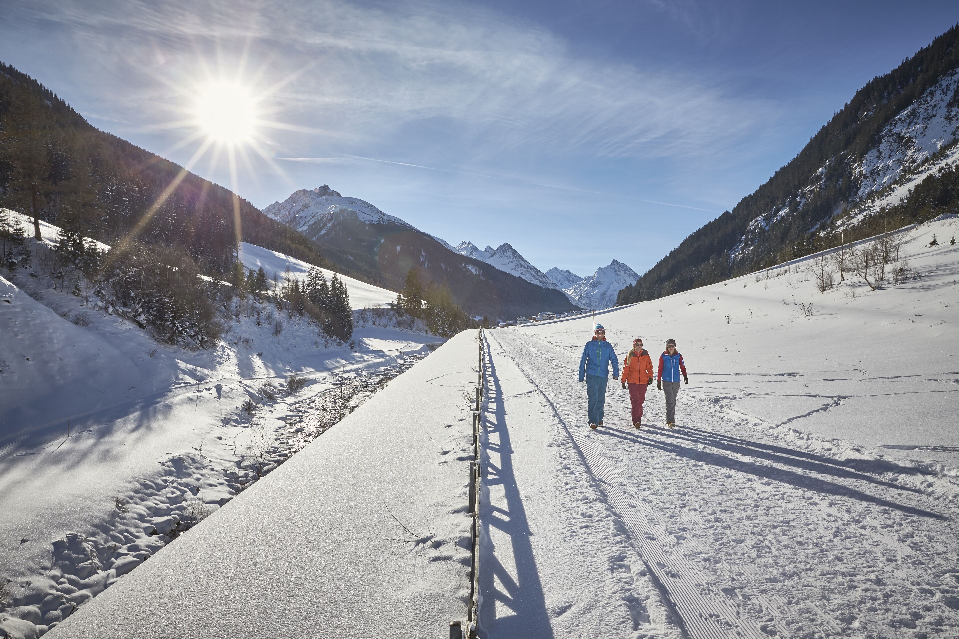 Un sentier enneigé avec des montagnes en arrière-plan.