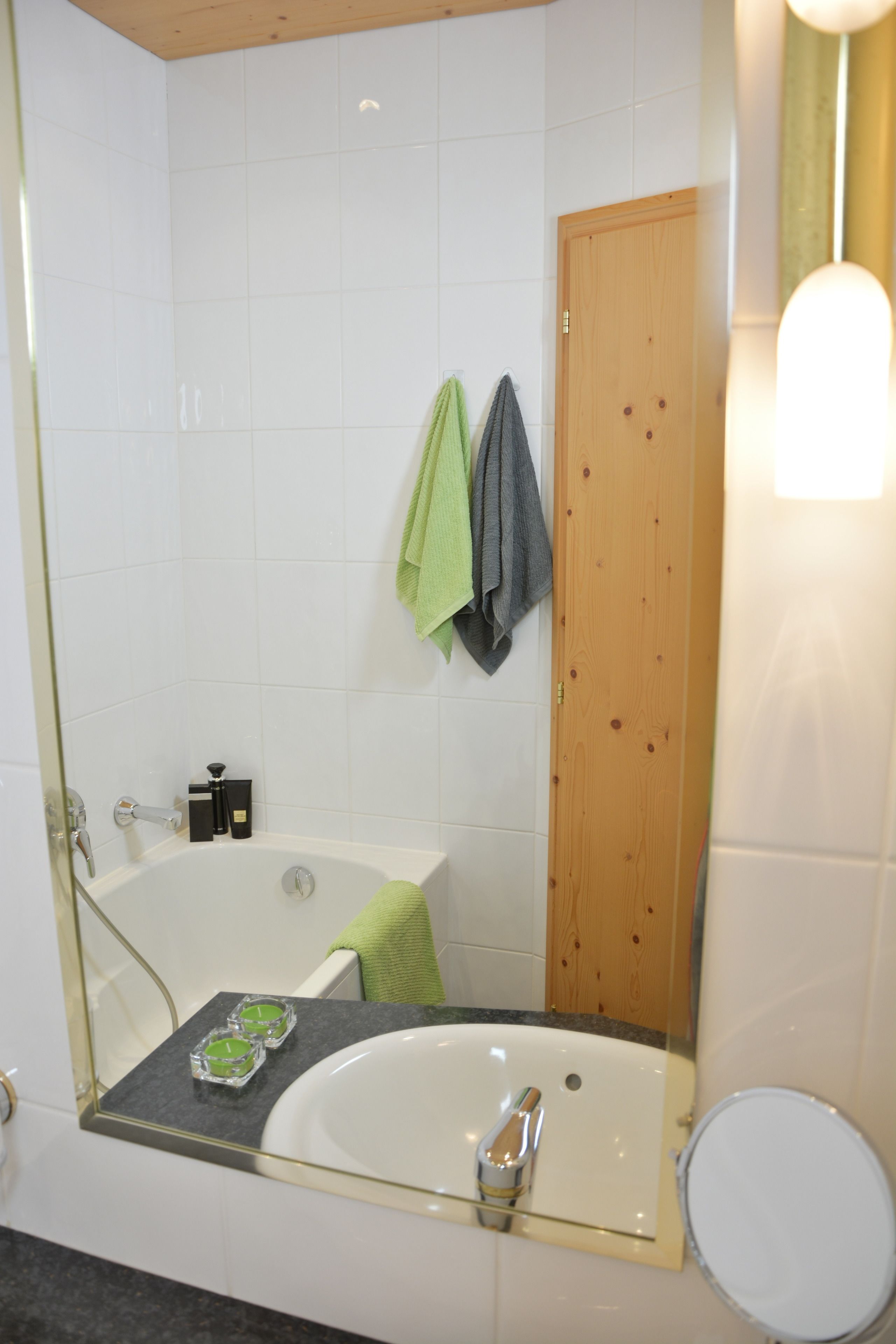 A bathroom with a bathtub, a sink, and a toilet. There are towels hanging on the wall and a wooden door.