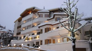 A multi-story hotel with balconies, snow-covered surroundings, and illuminated windows.
