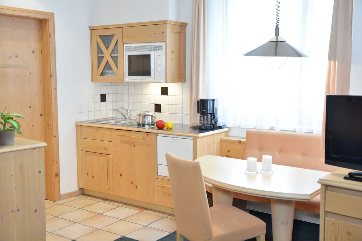 Una cocina compacta con armarios de madera, microondas, cafetera y un comedor con mesa y sillas.