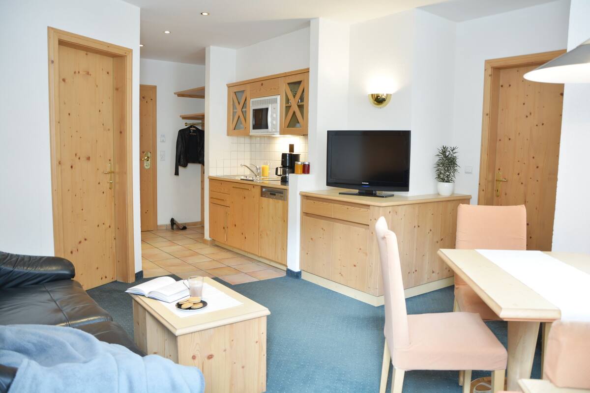 Un espacio habitable compacto con kitchenette, comedor y zona de estar.