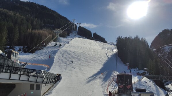 A ski slope with a chairlift, a snow-covered mountain, and a forested area.