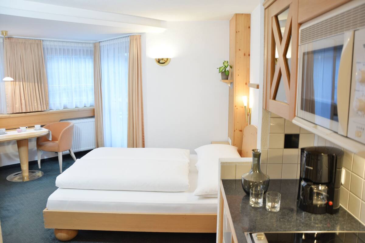 Una habitación de hotel con una cama, un escritorio, una silla, una cafetera y un televisor.