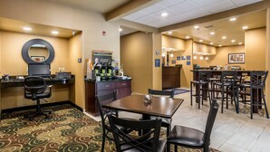 Un hall d’hôtel comprenant un comptoir d’accueil, un espace où l’on peut se servir du café et un coin repas avec des tables et des chaises.