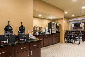 Un espace cuisine équipé d’un appareil à gaufres, d’une machine à café et d’un réfrigérateur.
