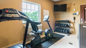 Une salle de sport équipée d’un vélo d’appartement, d’un appareil elliptique et d’un porte-haltères.