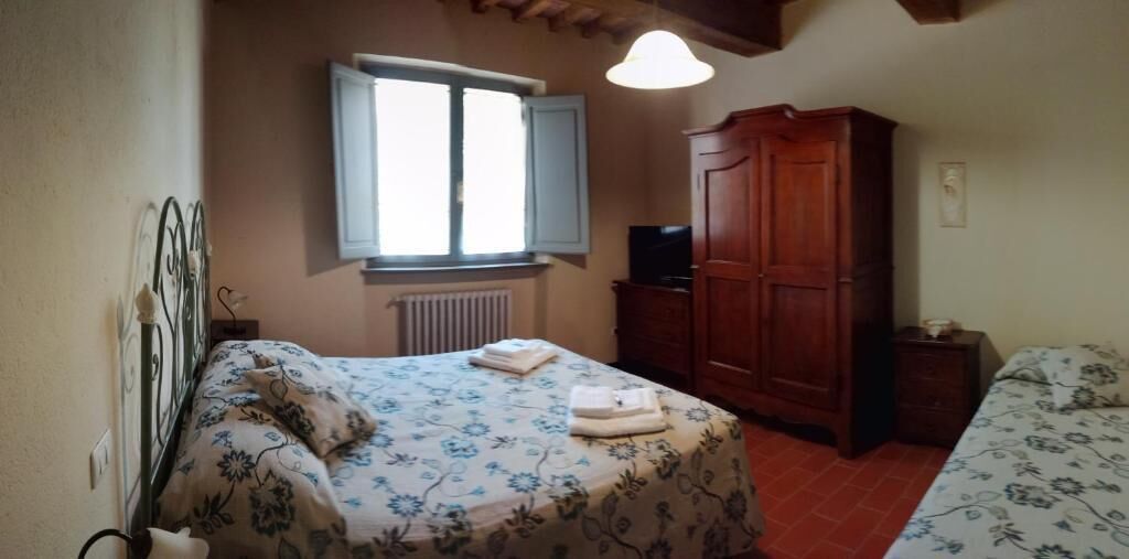 A bedroom with a bed, a wardrobe, a radiator, and a window.