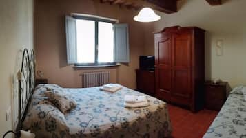 A bedroom with a bed, a wardrobe, a radiator, and a window.
