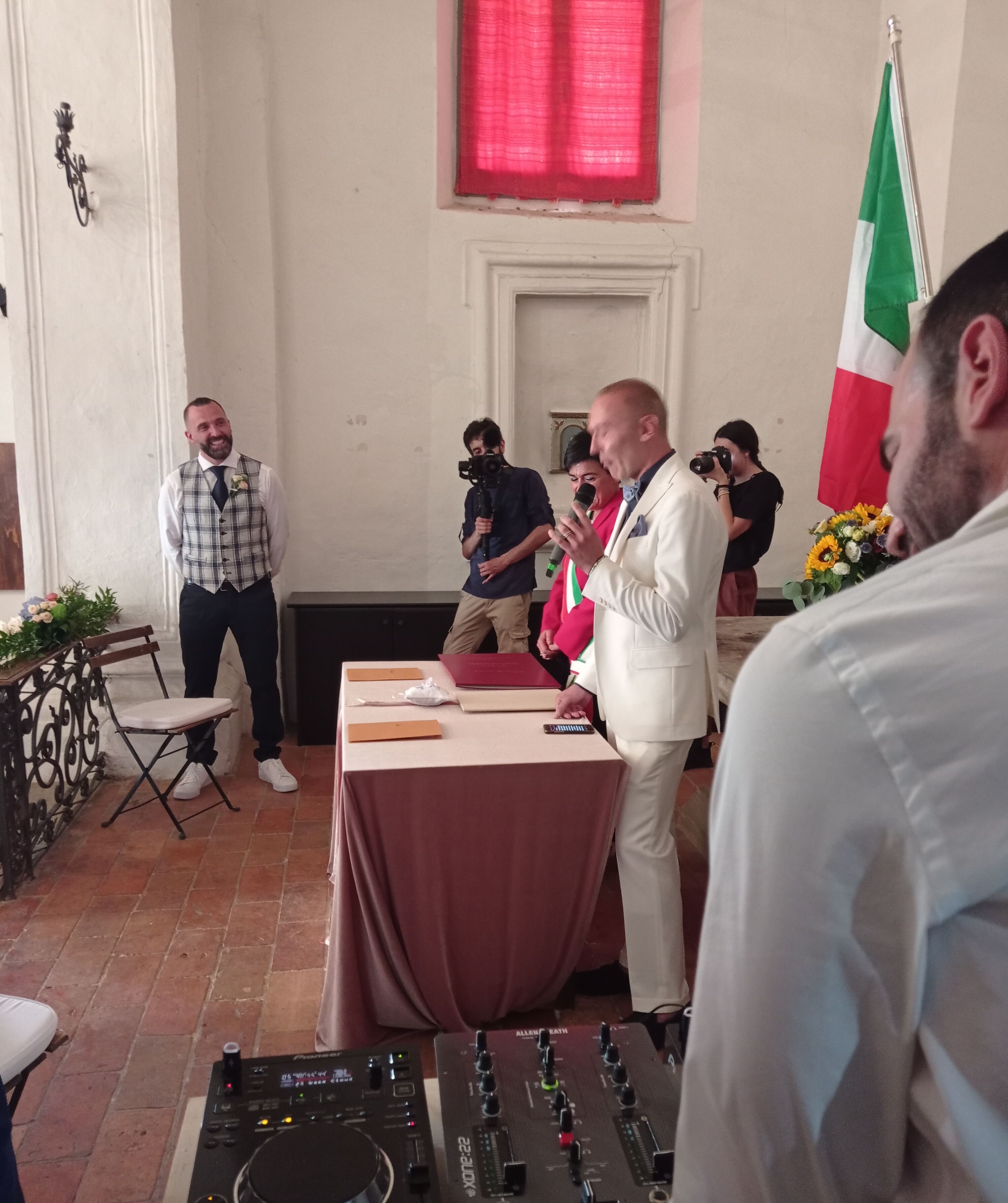 A room with a DJ setup, a table with a microphone, and a flag.