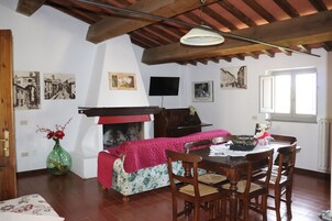 A cozy room with a fireplace, wooden furniture, and artwork on the walls.