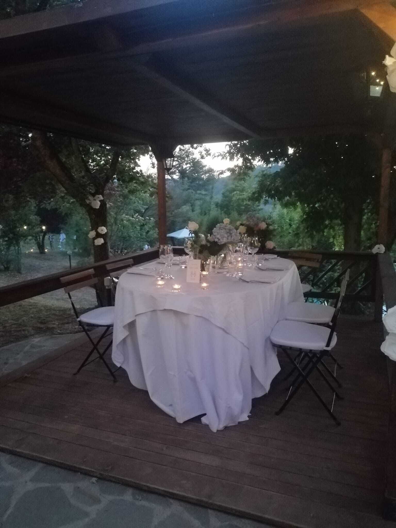 An outdoor dining area with a covered table set for six, surrounded by chairs.