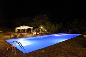 Piscina rectangular con una escalera en un lateral, rodeada por un patio de piedra.