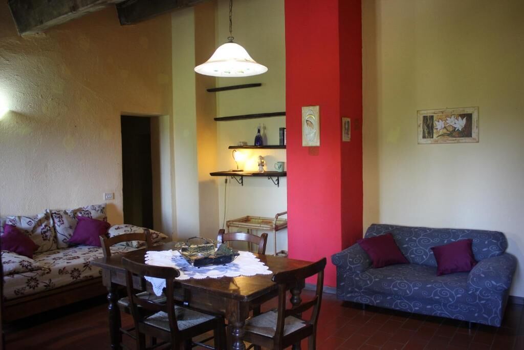 Una sala de estar con una mesa de comedor, dos sofás y una pared de acento roja.