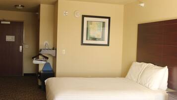 Une chambre d’hôtel avec un grand lit, une table de chevet, un lavabo fixé au mur et une porte.
