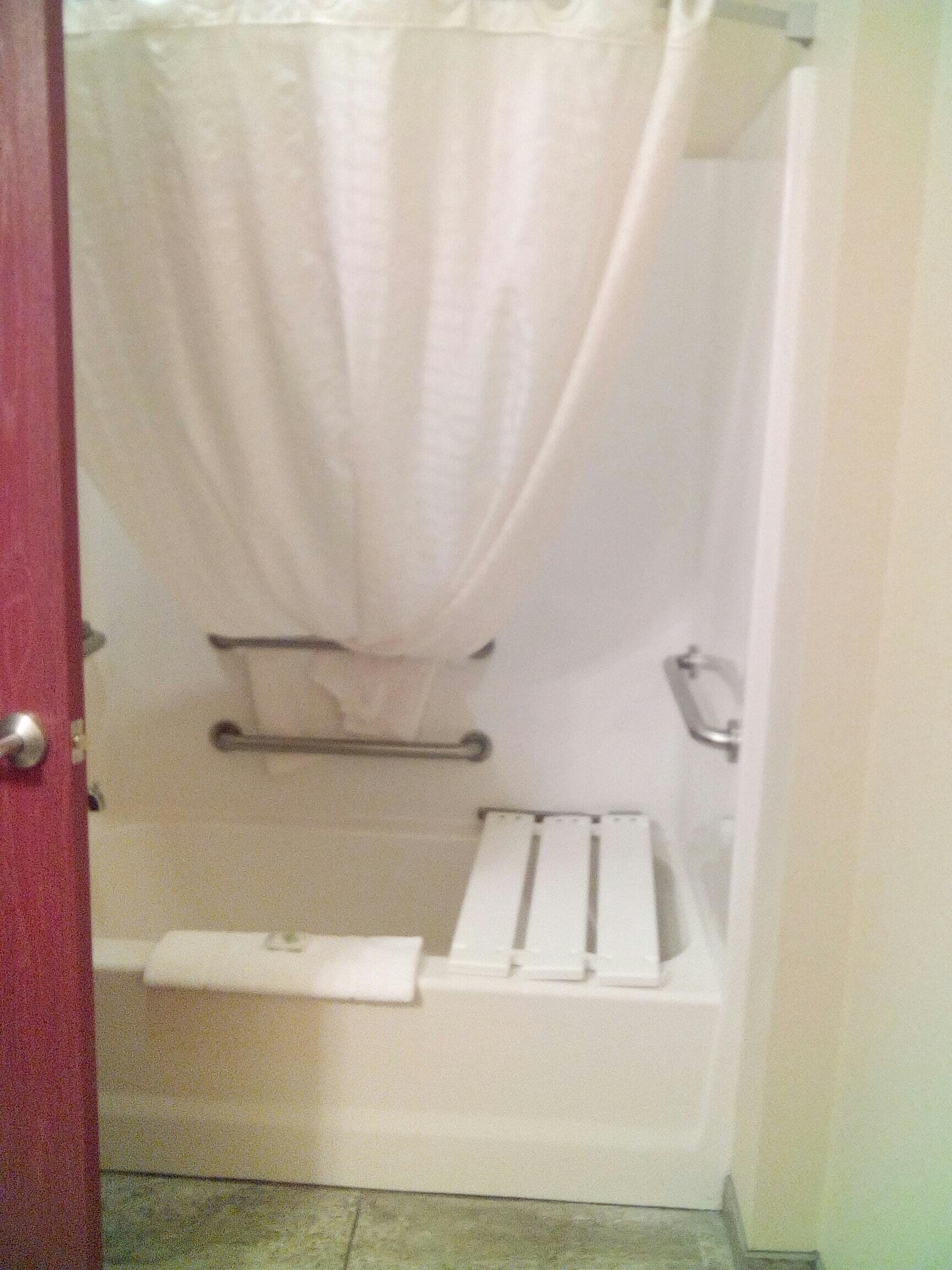 Un bagno con tenda della doccia, porta asciugamani e un asciugamano bianco.