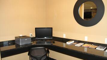 A hotel reception desk with a computer, printer, and a chair.