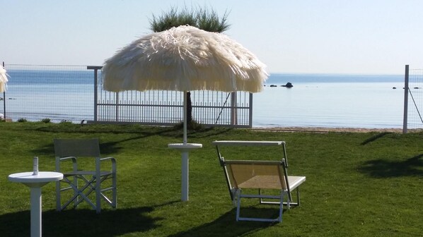 A grassy outdoor area with a white umbrella, two white chairs, and a small table. - Agriturismo Frontemare (Roseto degli Abruzzi)