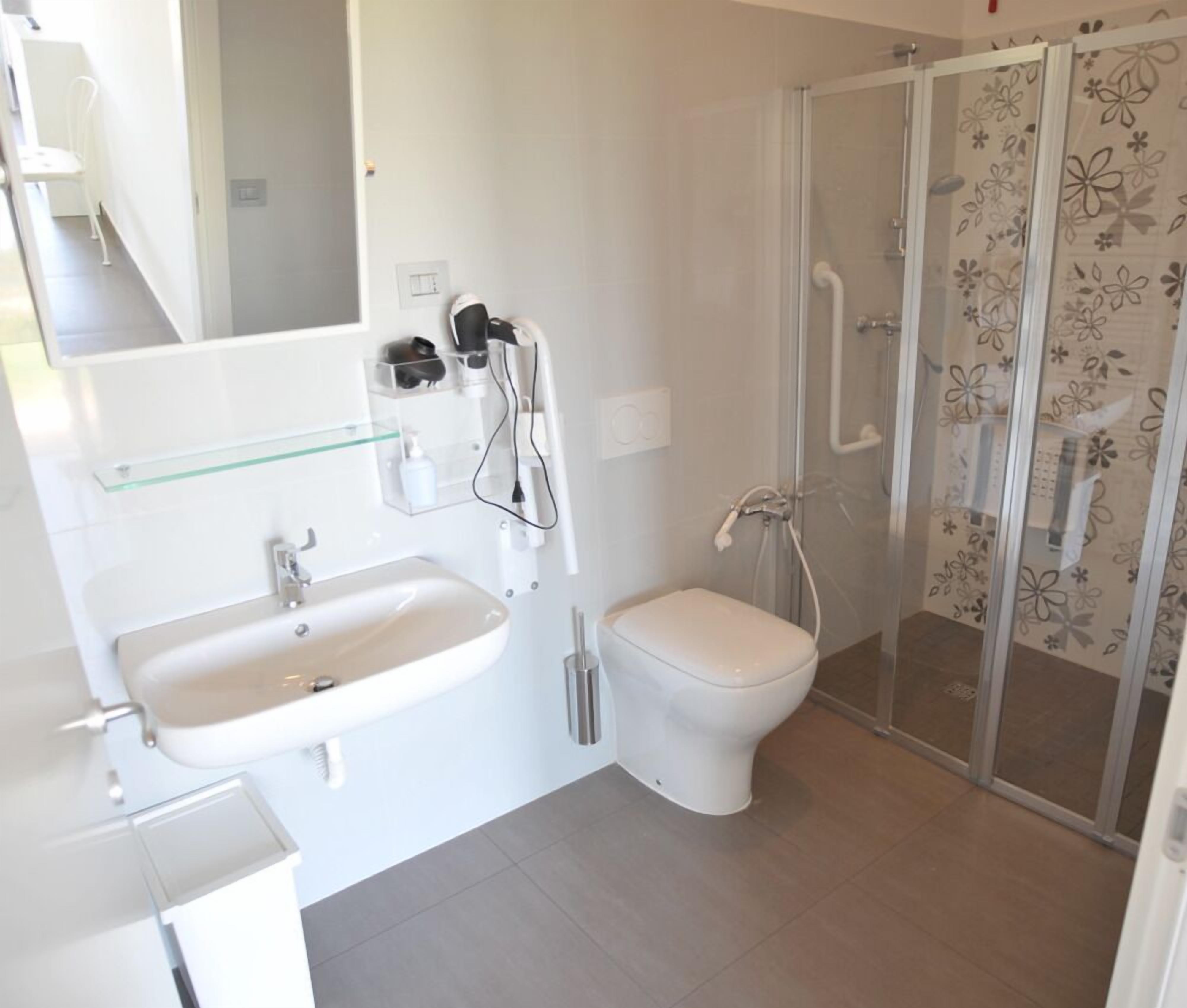 Ein modernes Badezimmer mit Duschkabine aus Glas, einem weißen Waschbecken und einer Toilette.