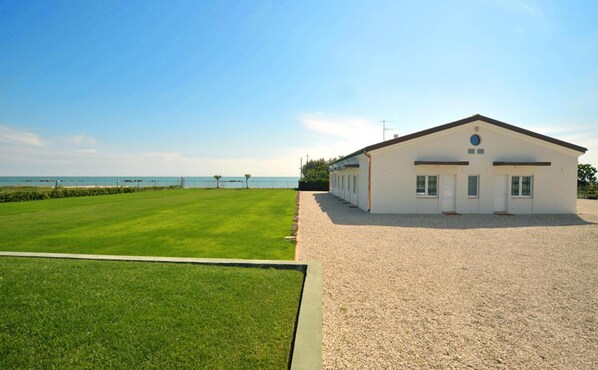 A single-story building with a white exterior, a gravel driveway, and a well-maintained lawn. - Agriturismo Frontemare (Roseto degli Abruzzi)