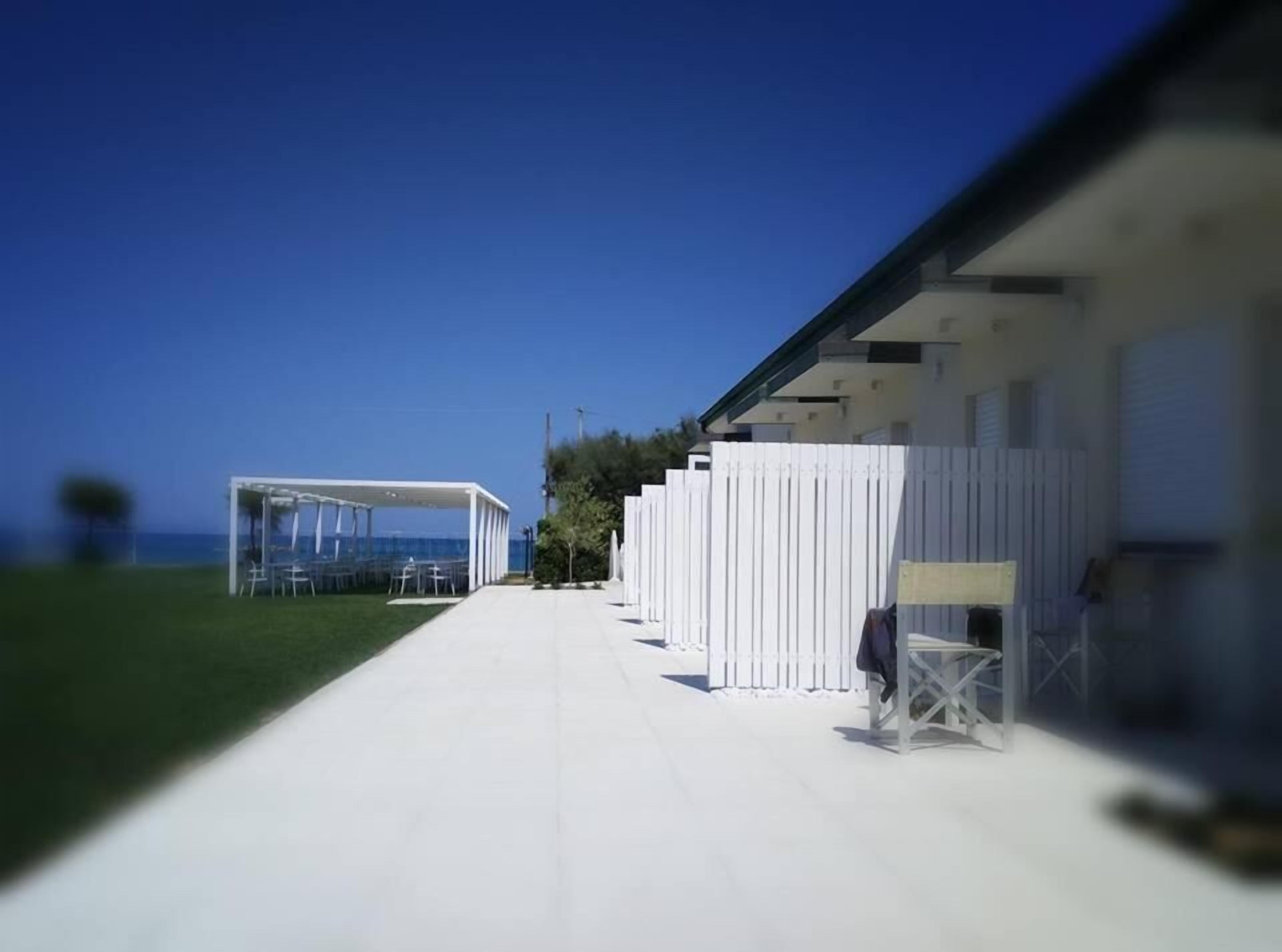 A modern building with a covered outdoor seating area and a white fence.