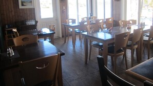 Un restaurant avec des tables et des chaises en bois, de grandes fenêtres et un panneau indiquant la sortie.