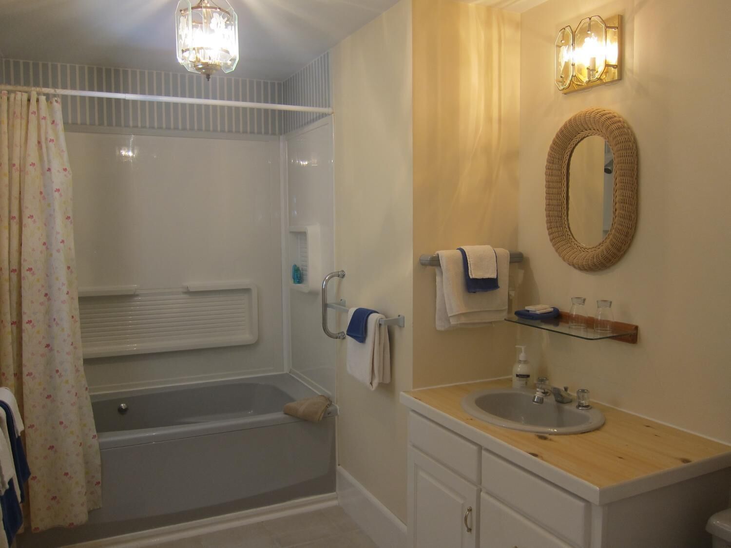 A bathroom with a bathtub, a vanity with a mirror, and a shower curtain.