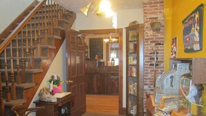 Un escalier avec des rampes en bois et un sol recouvert de moquette mène à une pièce dont un mur est en briques et qui contient une armoire en bois.
