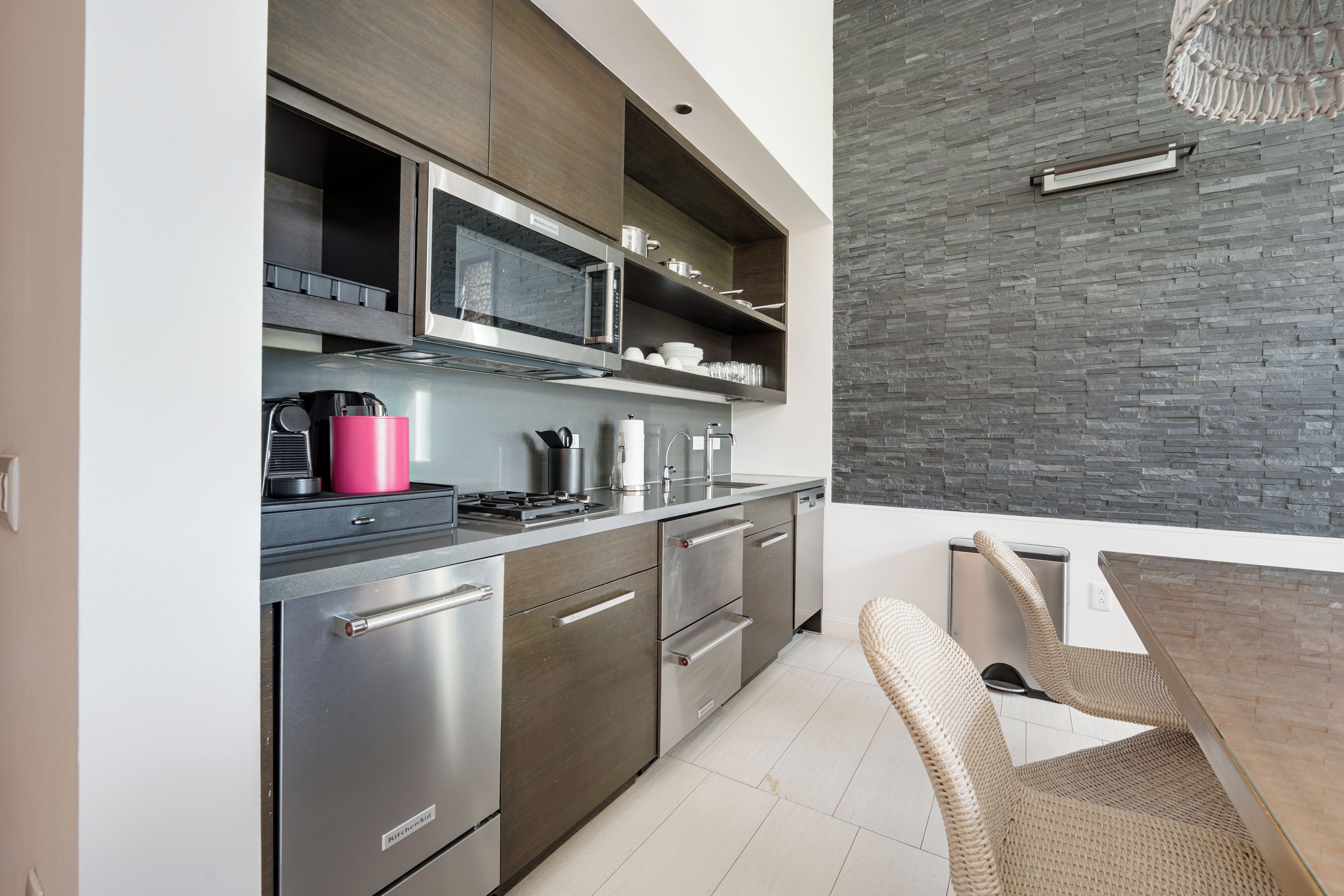 A modern kitchen with stainless steel appliances, a microwave, and a built-in oven. There is a dining area with a table and chairs.