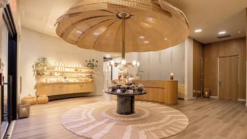 A lobby with a round table, a reception desk, and a large woven ceiling light fixture.