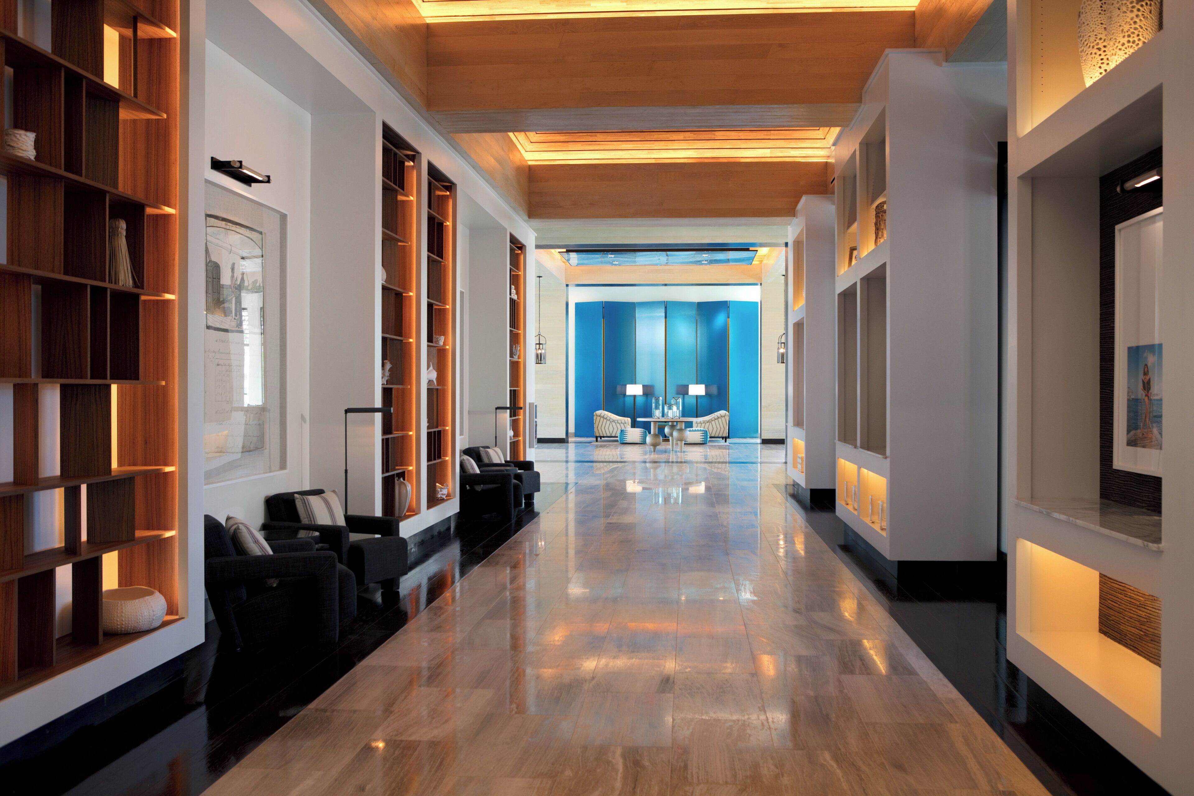 A hotel lobby with a polished marble floor, a reception desk, seating area, and a blue accent wall.