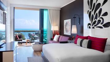 Una habitación de hotel moderna con una cama grande, un sofá, un comedor y vista al mar.