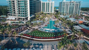 A modern hotel complex with multiple high-rise buildings, a central swimming pool, and surrounding palm trees. - Kimpton Seafire Resort + Spa by IHG (Seven Mile Beach)