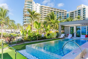 A swimming pool with a clear blue water, surrounded by white lounge chairs and palm trees. - Kimpton Seafire Resort + Spa by IHG (Seven Mile Beach)